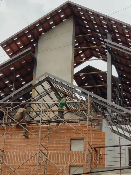 This photo captures a key moment during the renovation of the Earthen Spirit warehouse. Our team is installing the new steel framework for the sloping roof over the existing brick structure. This image shows the structural engineering and careful construction required to add new architectural layers to an old building.