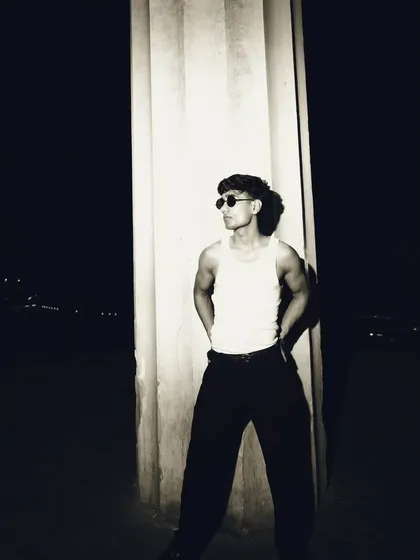 A profile shot that uses the column to create a strong vertical line. The lighting carves the subject out of the darkness.