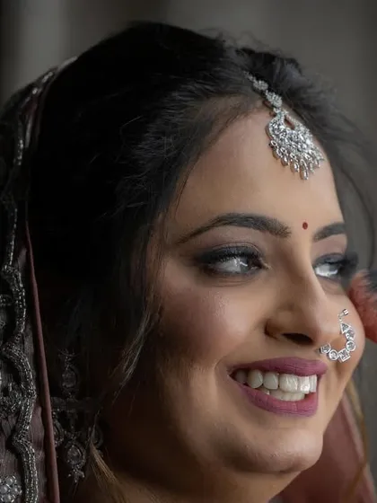 A close-up of the final makeup application, highlighting the bride's joyful expression and the precision of the artist's work.