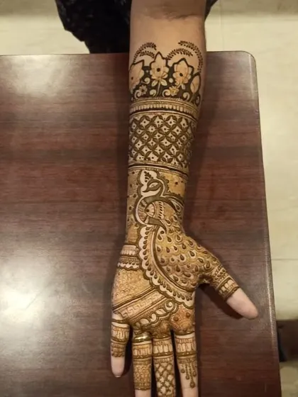 This intricate arm mehndi showcases a detailed peacock design, a symbol of beauty in Indian weddings. Our artists are experts in creating such elaborate traditional motifs.
