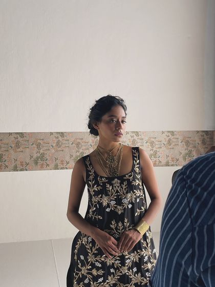 A candid moment on set, capturing the model in a beautiful ethnic wear look while the lighting is being adjusted.