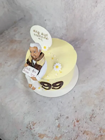 A simple and elegant cake for a 99th birthday, featuring a custom figurine of the gentleman holding a book with a Kannada script. It was a rare honour to make a cake for such a milestone.