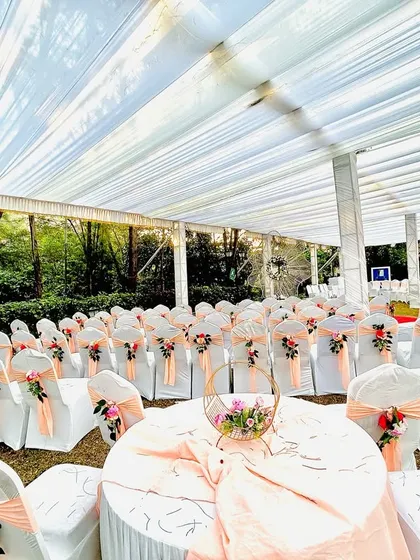 We pay attention to every detail, including guest seating. Here, we've arranged round tables and chairs with peach-colored sashes and floral accents for a wedding reception.