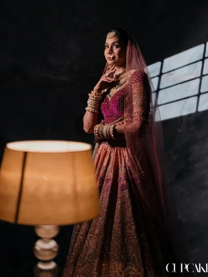 A beautifully lit portrait of the bride, showcasing the unique color palette of her Tarun Tahiliani lehenga. This is a look that is both artistic and personal.