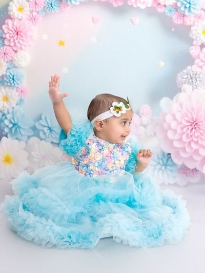A side profile from the pastel rainbow session, showing the baby looking towards the side. The layered blue dress and floral headband complete this fairy-tale look.