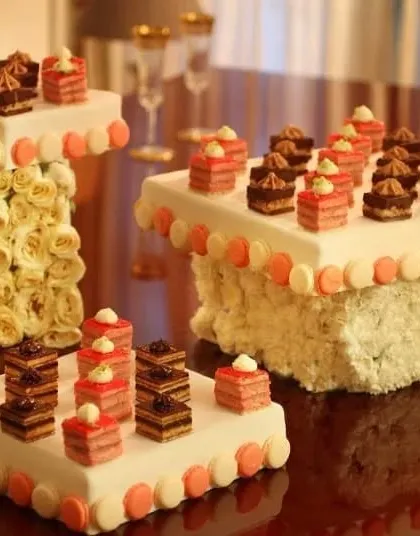 An architectural dessert display from our L'Opéra collaboration. Miniature cakes are presented on elegant, custom-built stands adorned with fresh roses, creating a stunning visual centerpiece.