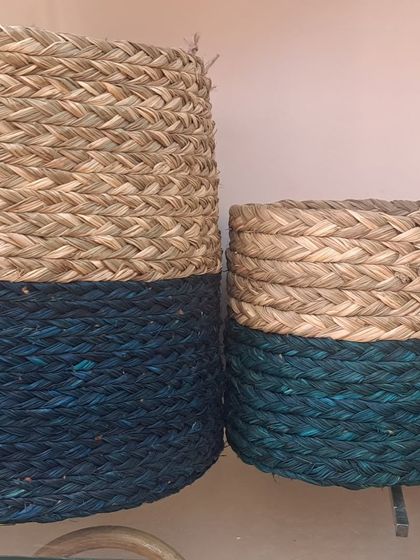 A set of two-tone cylindrical baskets in natural and deep teal. The color-dipped look is a modern take on traditional weaving, perfect for adding a contemporary touch to your storage solutions.