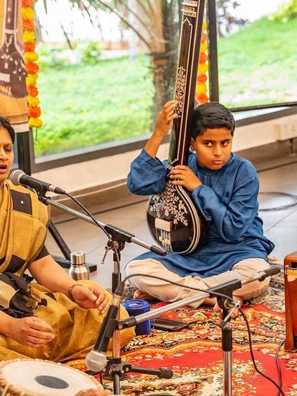 A young student holds the tanpura, fully present in the music. These moments of shared practice are where the true learning happens, connecting us to the lineage of teachers and the heart of the music.