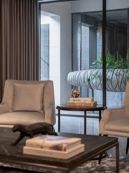 A detail shot of the living room, focusing on the textures of the furniture, the curated decor on the coffee table, and the view into the adjacent space.