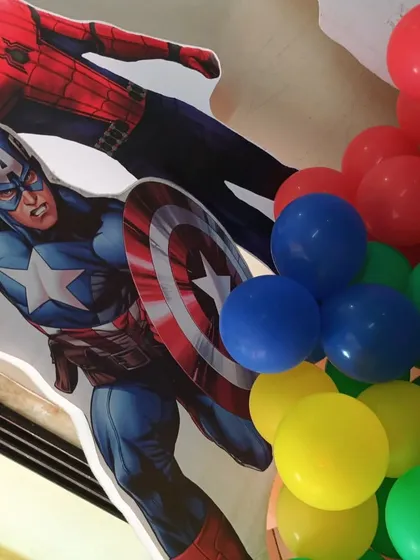 Placing the superhero cutouts next to the balloon arch during the Avengers theme setup.