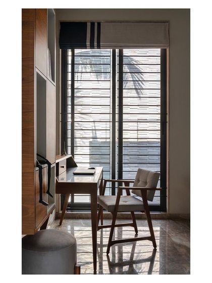 A study nook with custom built-in wooden furniture, offering a quiet and functional workspace. The large window provides ample daylight and a visual connection to the outside, making it an inspiring place for work or reading.