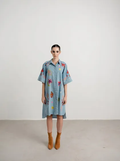 A full-length shot of a denim shirt dress with colorful embroidery. I paired it with brown boots to create a look that feels both contemporary and slightly rustic.