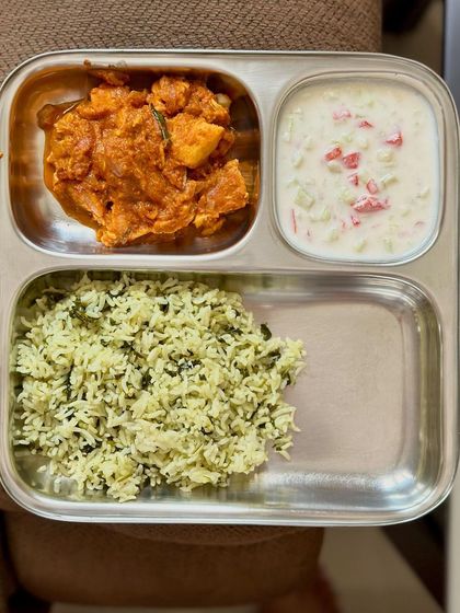 This plate features dill-flavored rice with a side of chicken ghee roast and cucumber raita.