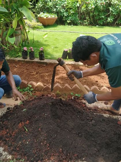 Two of our team members are preparing a garden bed, mixing compost and fertilizers into the soil. This careful preparation ensures that new plants and lawns have the nutrients they need to thrive.