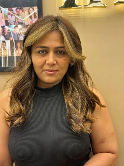A client showing off her new hair color, which features face-framing highlights and a soft, wavy style.