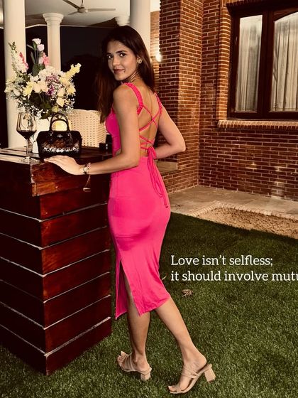 A reflective moment in a stunning pink backless dress. The vibrant color and daring silhouette make a statement, perfect for a special evening or a vacation dinner.