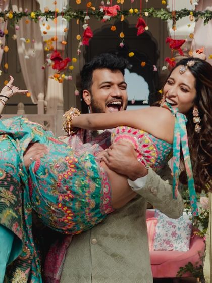 A fun and candid moment where the groom lifts the bride during their Mehendi performance. It's these spontaneous displays of joy that make the best memories.