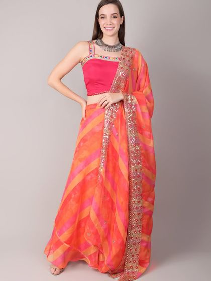Celebrate the first day of Navratri in this auspicious orange and pink lehenga. The striped skirt has a beautiful flow, and the dupatta is bordered with intricate sequin work.