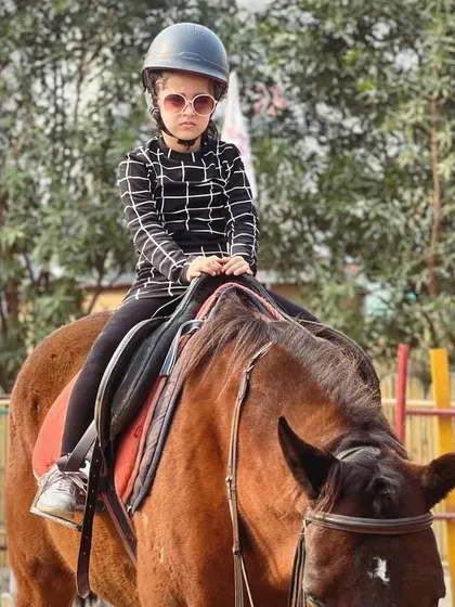 This stylish young rider shows off her cool sunglasses and confident posture, ready for her equestrian photoshoot.