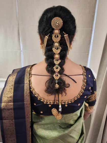 A detailed view of a traditional South Indian bridal braid. This hairstyle features a neat, tight braid decorated with exquisite gold-plated jada billalu, creating a timeless and regal look perfect for the main wedding ceremony.