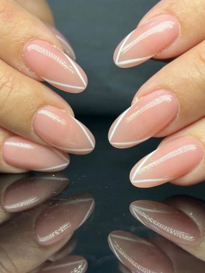 A minimalist and modern French manicure, featuring a simple white chevron line on a sheer pink base.