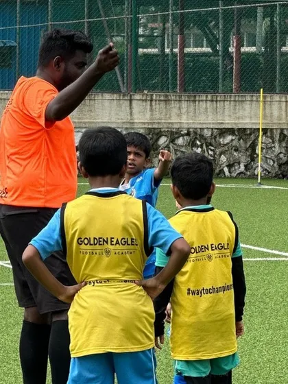 A coach gives instructions to our younger players. Clear communication and guidance are central to our coaching philosophy, ensuring every child understands the drill.