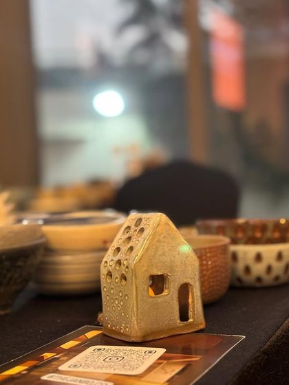 A tiny, handmade ceramic house, glowing from within at our flea market stall. These little luminaries are perfect for creating a cozy, magical atmosphere.