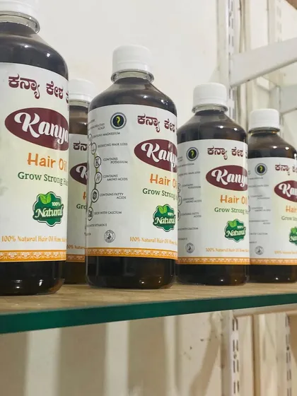 A side view of the larger Kanya Hair Oil bottles lined up on a shelf, showing the product label.