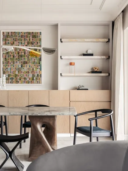 A closer look at the dining area in Apartment O2. The design is a harmony of clarity and warmth, with a glass and wood table base and colorful artwork.