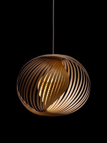 The Adilo pendant by Secto Design, shown against a black background, reveals its intricate, spiral structure. The ultra-thin birch plywood is crafted with geometric precision, creating a dynamic play of light and shadow.