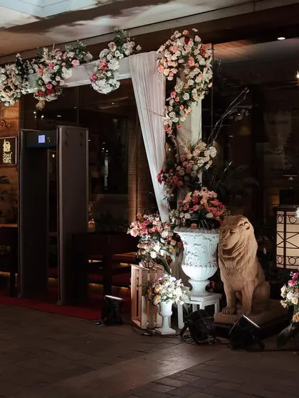 This is how we create a complete arrival experience. The setup includes a large floral arch, personalized welcome signage, and smaller arrangements leading guests toward the security check and into the venue.