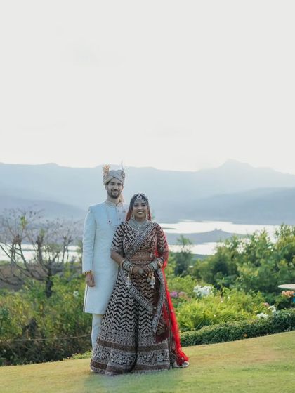 A stunning wide-angle portrait of the couple against a breathtaking landscape of mountains and water.