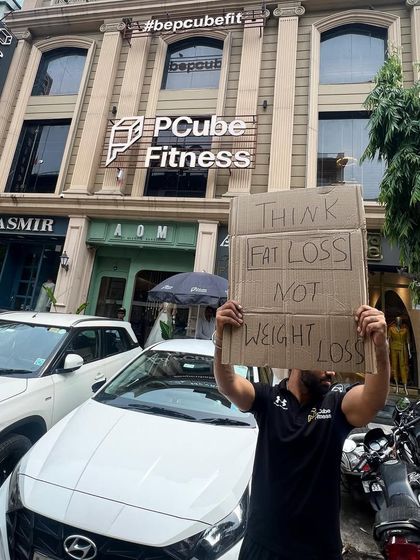 Our philosophy is simple: Think fat loss, not weight loss. A trainer stands outside our club, sharing a core principle of our training approach.