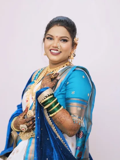 A full view of the bride's white and blue saree look, complete with green bangles and traditional gold jewellery.