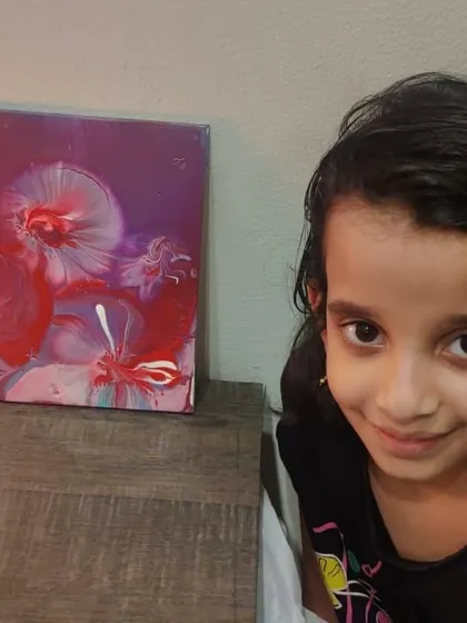 A young participant poses proudly next to her beautiful red and purple fluid art creation. It's so rewarding to see the confidence that making art can inspire.