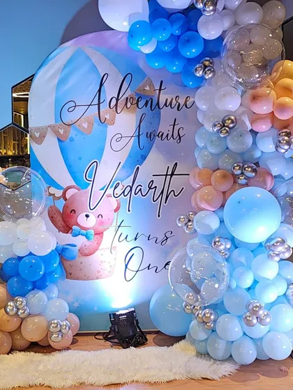 The full backdrop for Vedarth's birthday, showcasing the scale of the balloon arrangement and the custom-printed hot air balloon design.