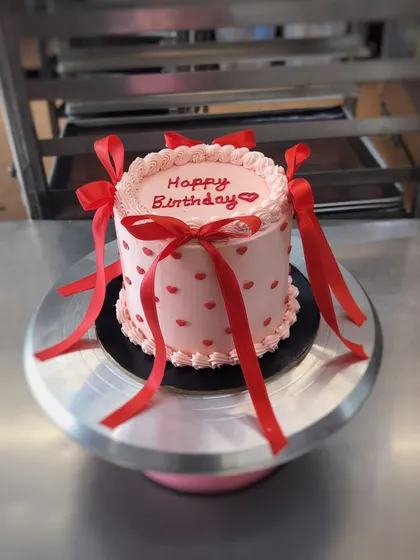 This pretty-in-pink birthday cake is all about love. Decorated with tiny red hearts and elegant red ribbons, it’s a sweet and stylish way to say "Happy Birthday."