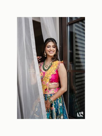A bright and joyful portrait of the bride-to-be, her smile lighting up the frame. The soft light from the window gives her a radiant glow, perfect for a pre-wedding celebration.