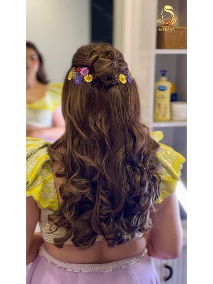 A back view of the fairytale hairstyle, with a braided bun and a line of colourful flowers.
