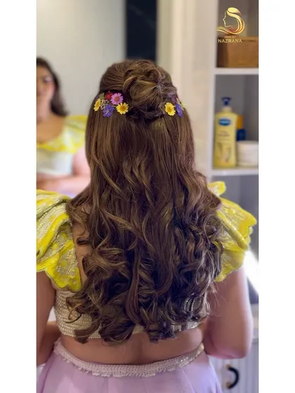 A back view of the fairytale hairstyle, with a braided bun and a line of colourful flowers.