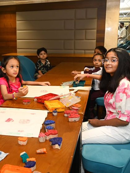 A young girl looks up from her painting, while others around her are busy creating. Our workshops are designed to hold children's attention and provide a space where they can explore art at their own pace.