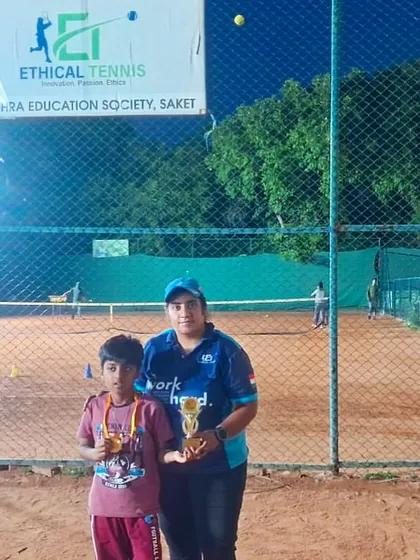 A player and coach pose with their trophies on our floodlit clay court at the Saket center. This night-time shot shows our commitment to playing and training no matter the time of day.