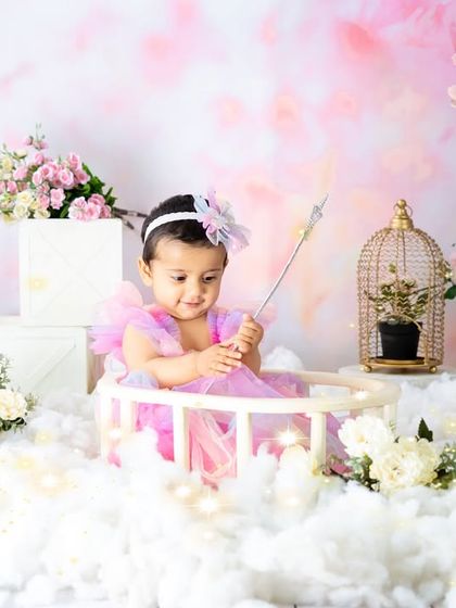 Making magic happen in a fairy garden. This wider shot shows the full setup, with twinkling lights, fluffy clouds, and floral arrangements creating a fantasy world.
