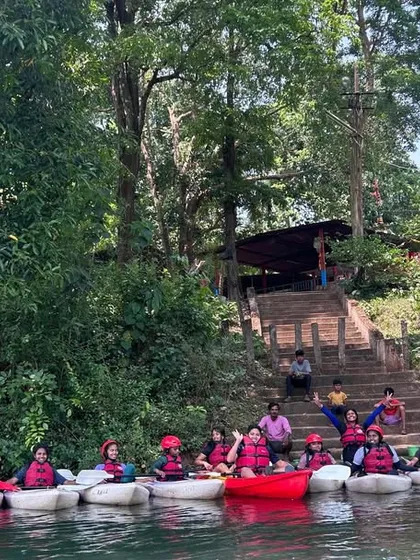 A group of students lines up in their kayaks, ready for instruction on the Kali River. This is the start of a session where they will learn essential paddling and navigation skills.