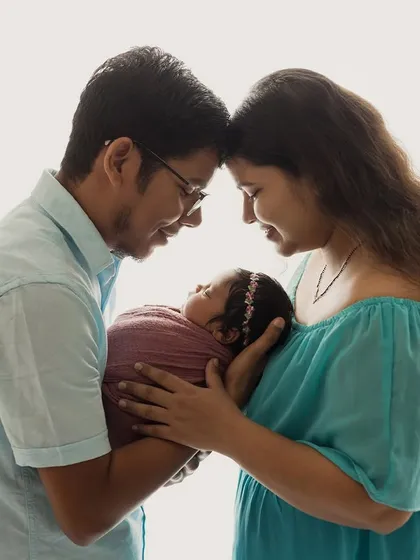 Embracing the miracle of new life. This family portrait is full of warmth and love, with the parents gazing at their new baby.
