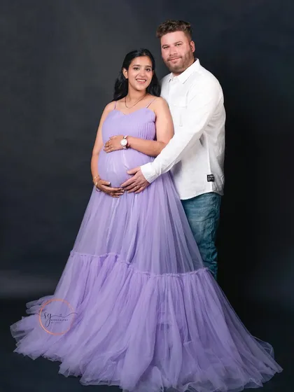 A beautiful studio portrait of an expecting couple. The flowing lavender gown adds a touch of elegance, and the pose highlights the baby bump and the connection between the parents-to-be.