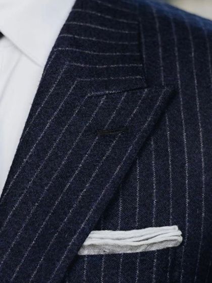 A detailed view of the lapel and pocket square on a custom pinstripe suit. It’s these small, perfected details that elevate a suit from standard to exceptional.