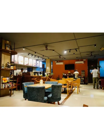 A wide view of the main cafe area, showing the mix of comfortable seating, the counter where the magic happens, and the overall spacious and airy feel of the place.