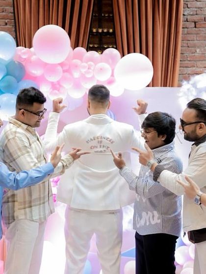 The dad-to-be showing off the back of his custom jacket, surrounded by his friends. It’s a fun and personal touch that adds to the celebratory atmosphere.