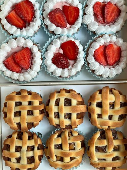 A close-up of our bite-sized treats. This box features mini strawberry tarts with fresh cream and mini apple pies with a classic lattice crust.